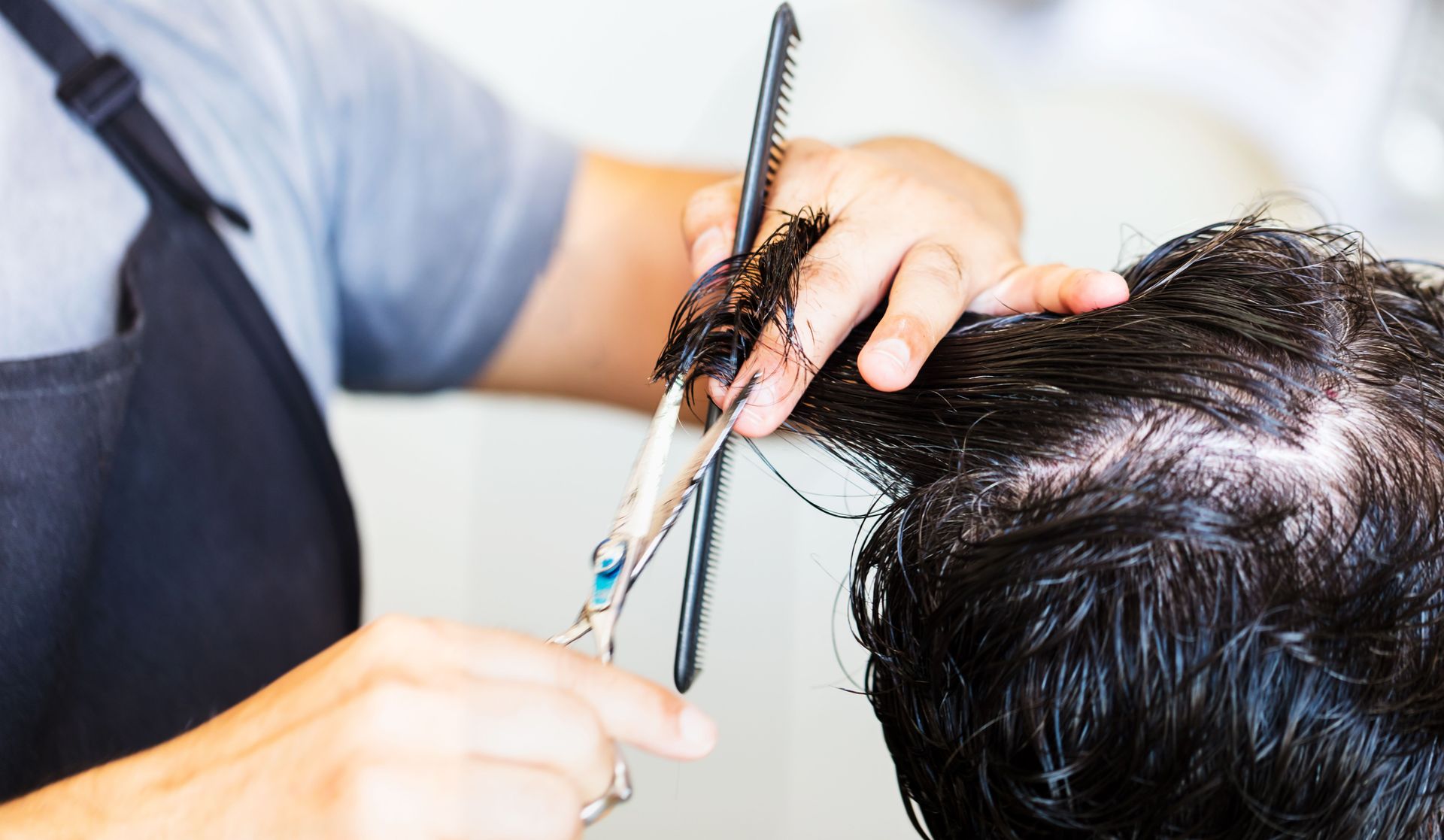 Close-up of hairstylist cutting hair with scissors and comb, showcasing precise technique.